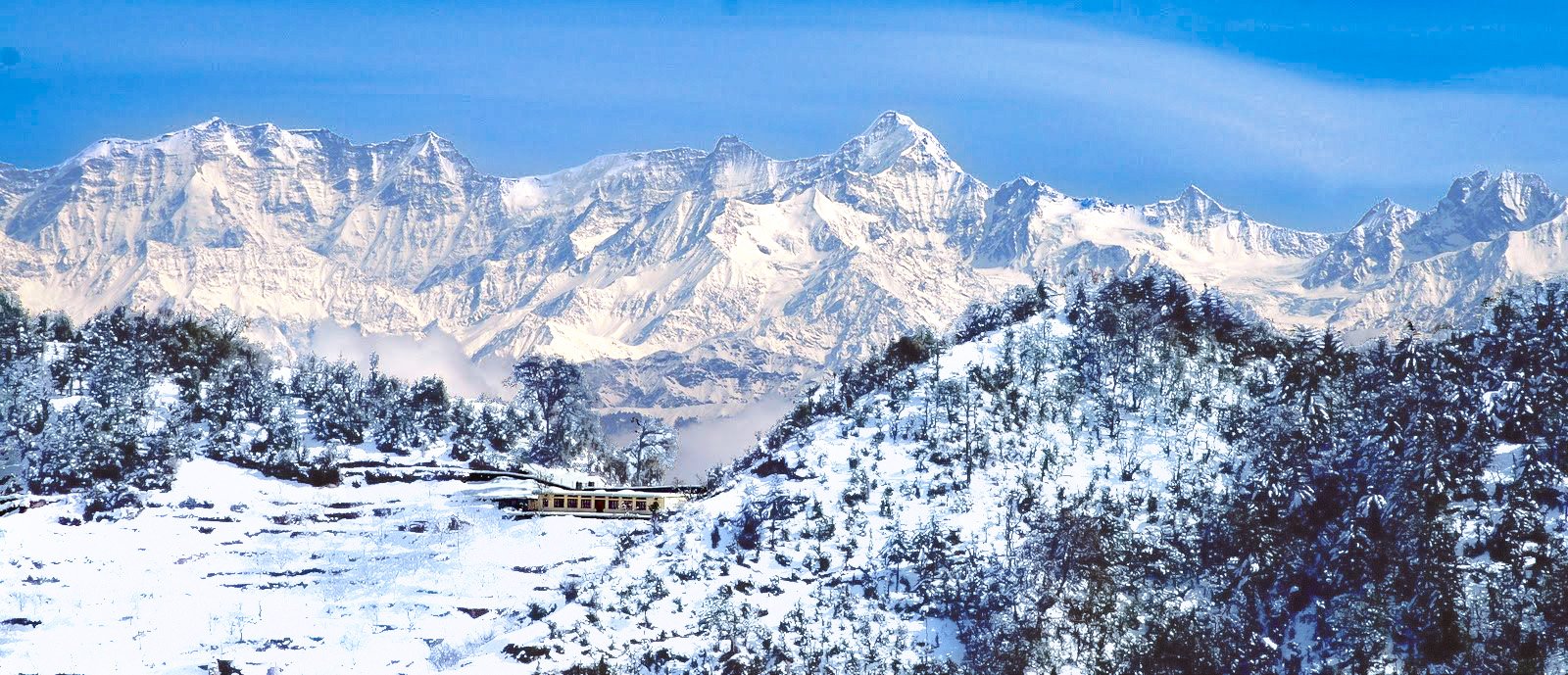 Panoramic cinematic view of snow-capped Himalayan peaks and mountain resort in Kanatal